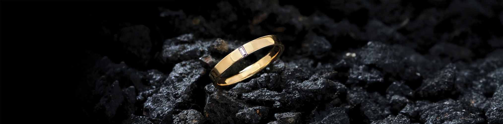 Alliance homme or jaune poli posée sur pierre volcanique noire, bague masculine joaillerie moderne