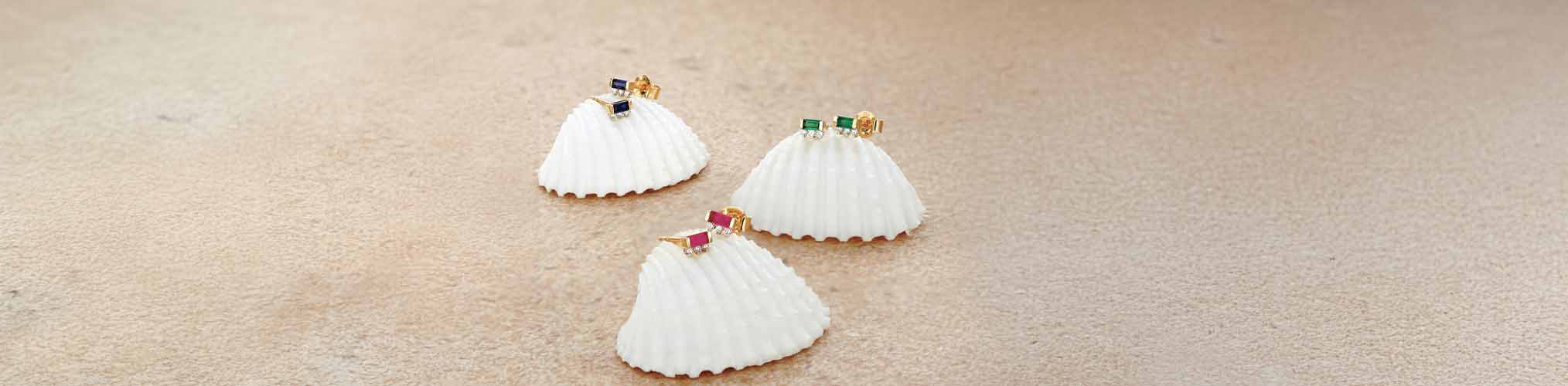 Clous d'oreilles or jaune 18 carats avec pierres précieuses saphir bleu émeraude et rubis sur coquillages blancs