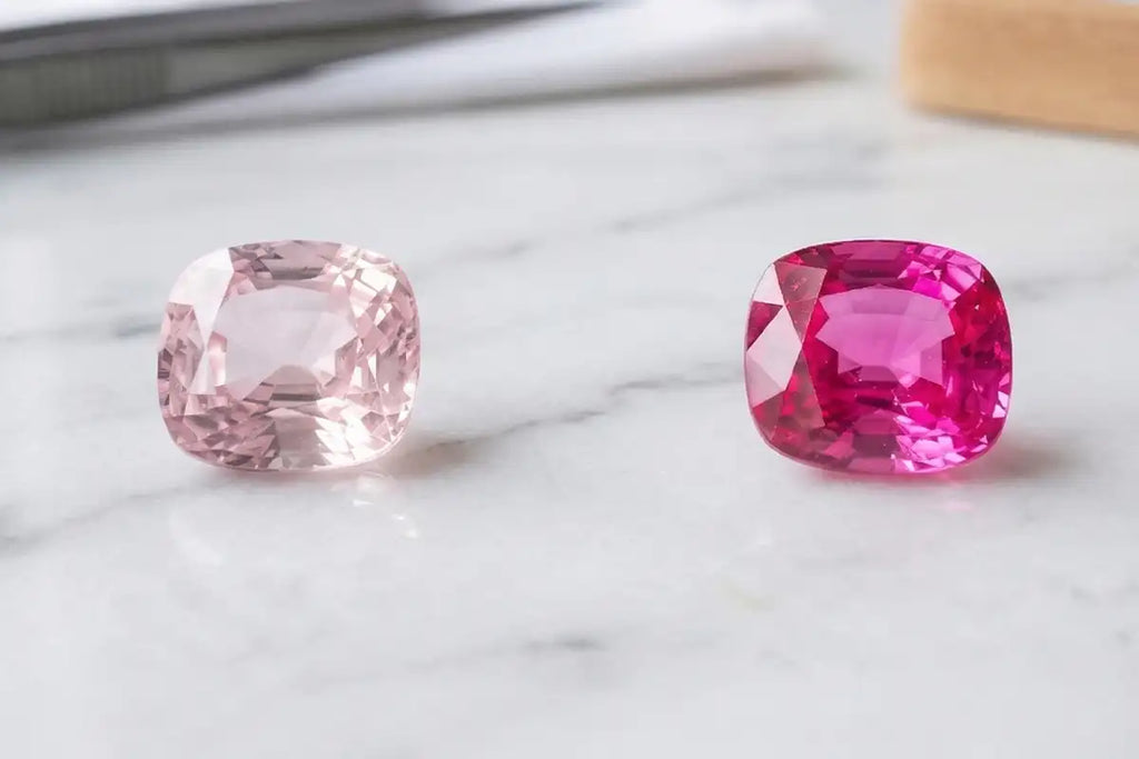 Comparaison entre un saphir rose pale et un saphir rose intense, poses sur marbre blanc, montrant l'eventail des tonalites