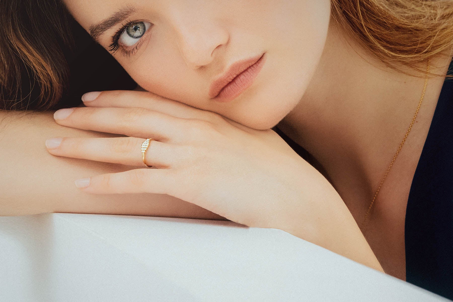 Bague de fiançailles collection Destinée en or jaune 18 carats avec pavé de diamants, portée par modèle aux yeux bleus