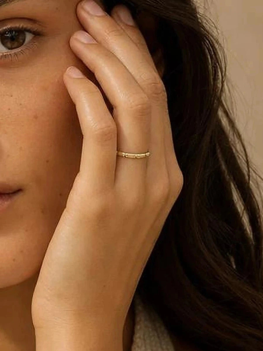 Bague Sobek 1,5 mm en or jaune portée, main contre le visage, recadrage sur l'anneau
