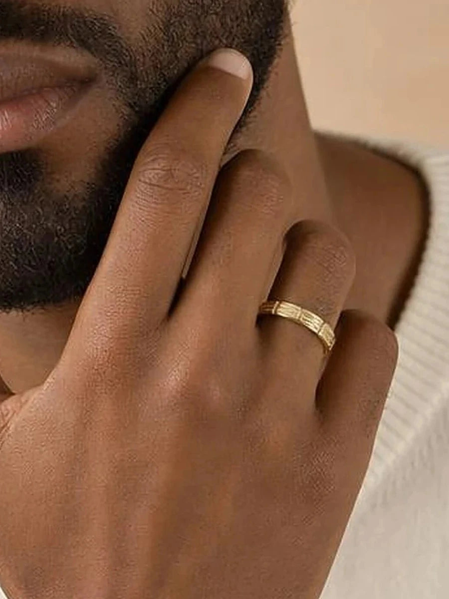 Bague Sobek 2,7 mm en or jaune portée par un homme, main contre le visage, recadrage sur l'anneau
