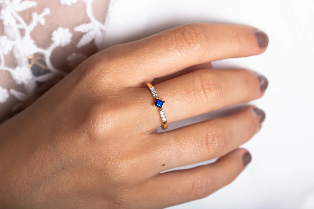 Bague Kali en or 18 carats sertie d'un saphir taille princesse et de diamants, portée à la main