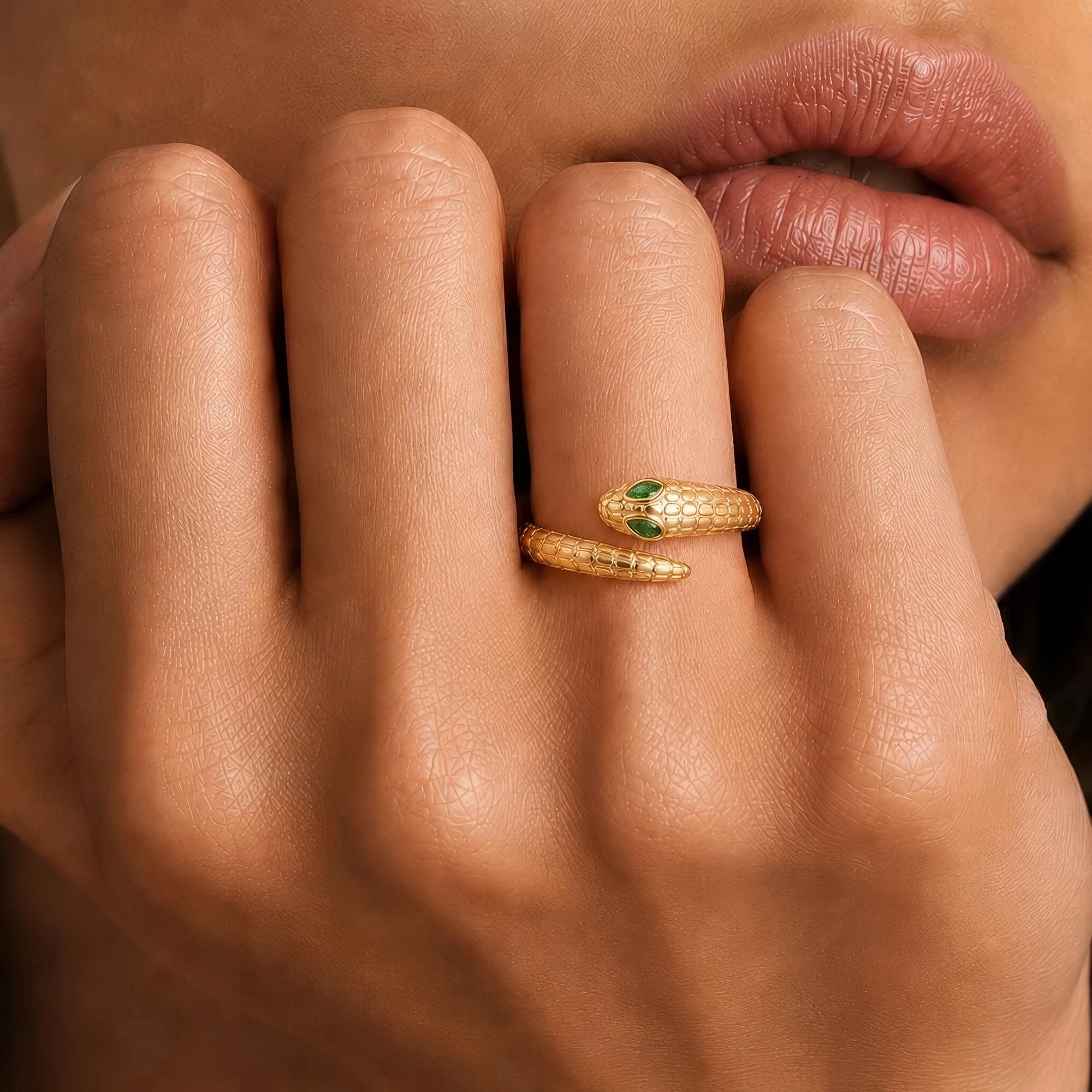 Bague serpent or jaune Méhen portée au doigt, émeraudes marquise en yeux