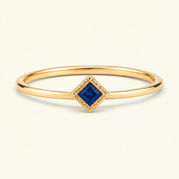 Bague de fiançailles vintage Indrani — solitaire saphir taille princesse 4 mm, pierre carrée sertie grènetis (milgrain), en or jaune 18 carats