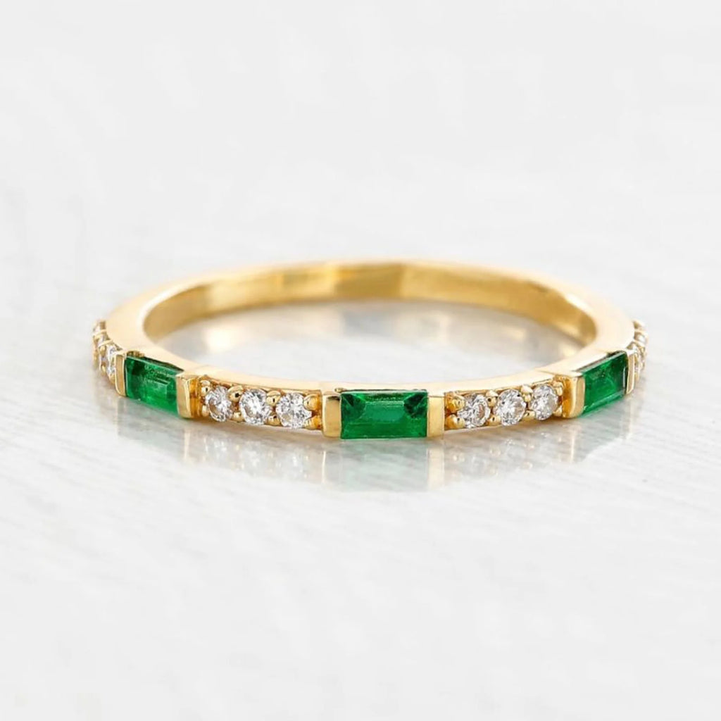 Bague en or jaune et émeraude sur peau à sous-ton chaud, illustrant l'harmonie naturelle