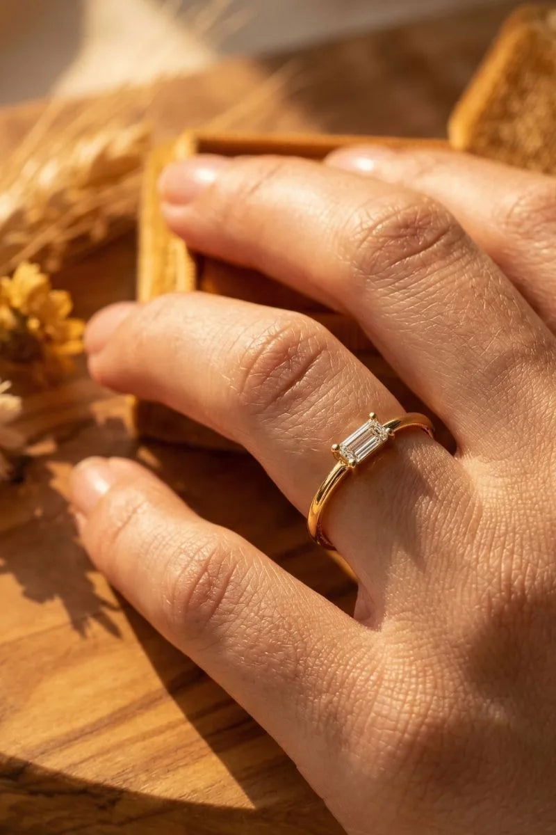 Bague solitaire diamant baguette en or jaune portée au doigt, illustration du choix d'un diamant