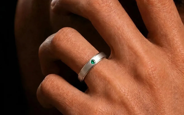 Jonc en or blanc 18 carats serti d'une émeraude porté au doigt par Mayuri