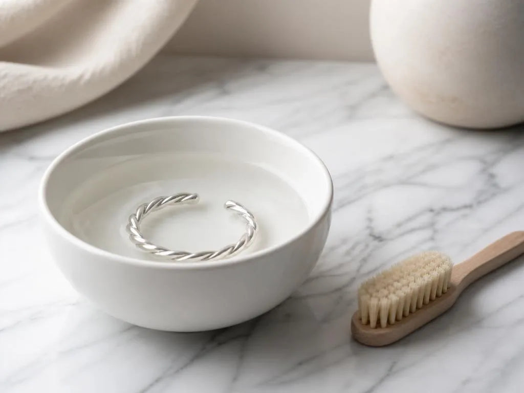 Bracelet tressé en argent 925 dans un bol d'eau avec brosse douce pour nettoyage