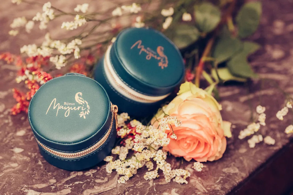 Deux écrins ronds Mayuri en velours turquoise posés sur fond lifestyle avec fleurs séchées et roses