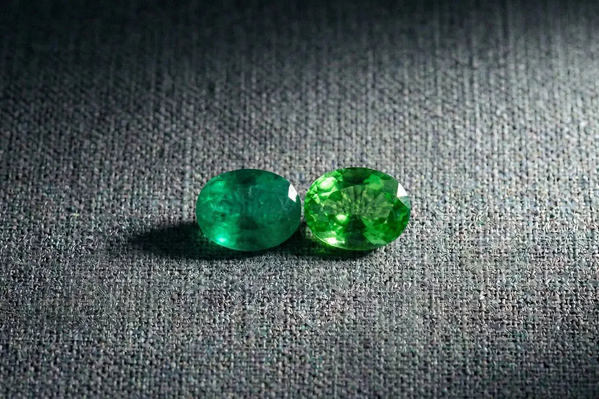 Émeraude et tsavorite posées côte à côte, comparatif couleur et transparence