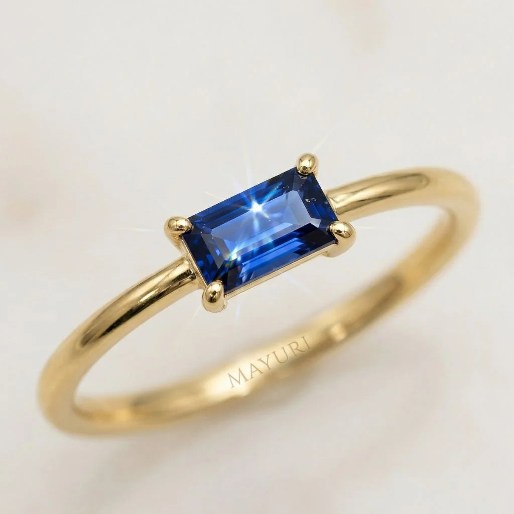 Gros plan d'une bague Mayuri en or jaune 18 carats sertie d'un saphir bleu baguette éclatant