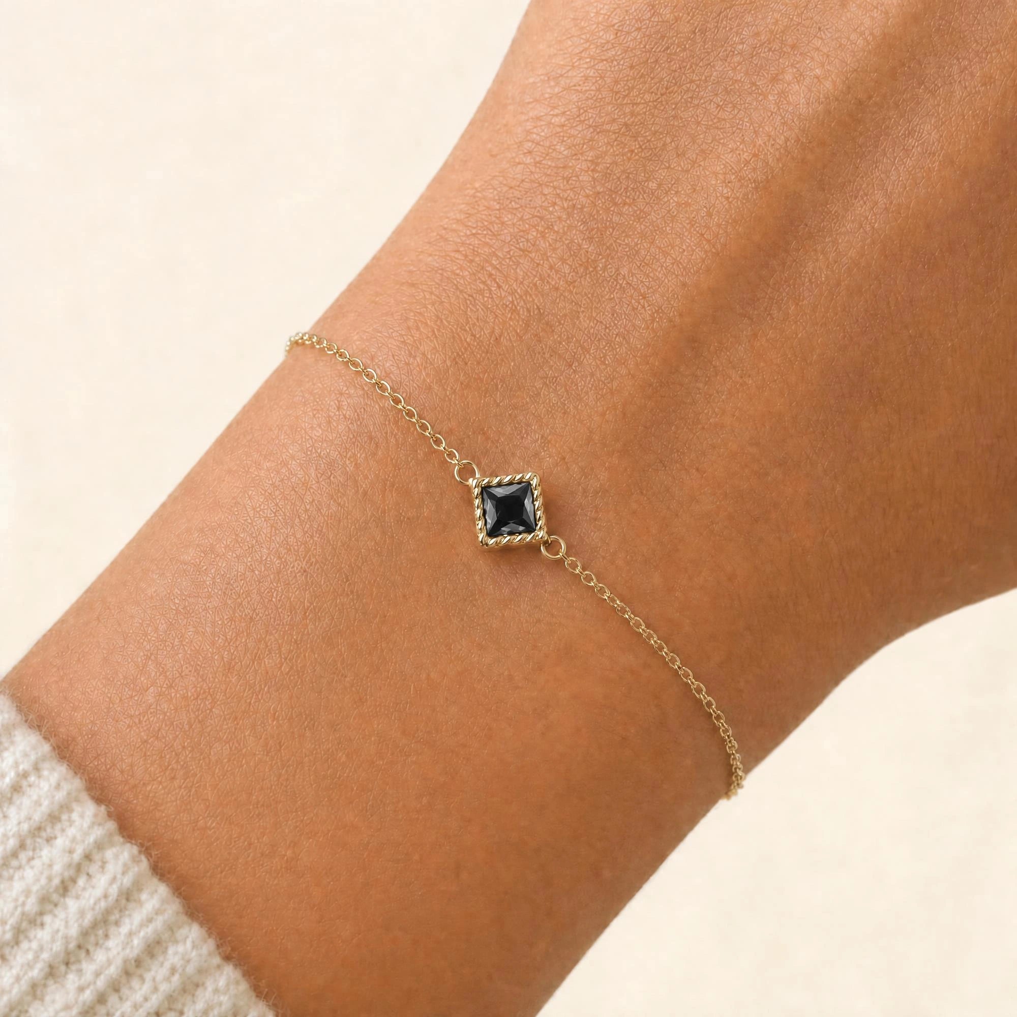 Bracelet diamant noir Indrani porté au poignet, solitaire princesse serti torsade en or jaune 18 carats