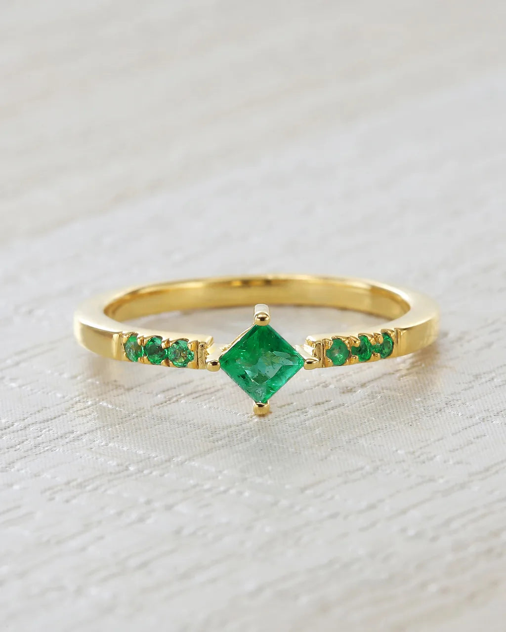 Bague Kali en vermeil doré sertie d'émeraudes naturelles sur fond lin clair