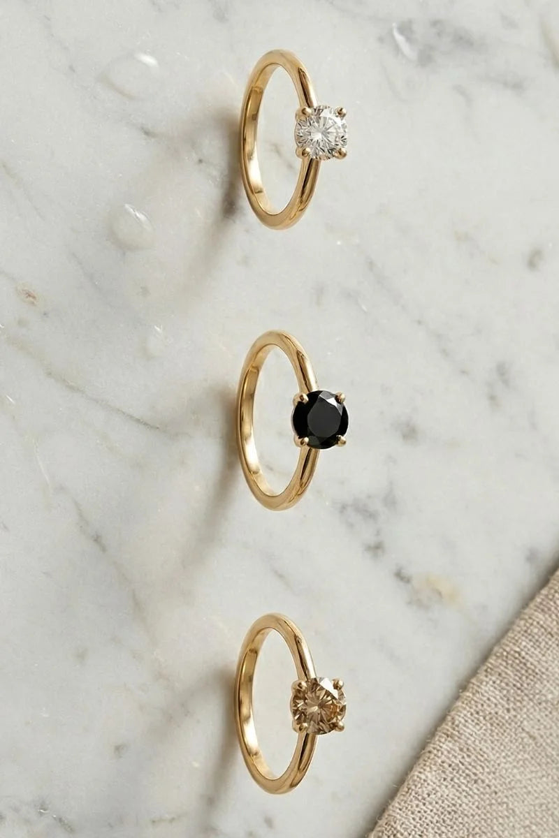 Trois solitaires en or jaune : diamant blanc, diamant noir et diamant champagne
