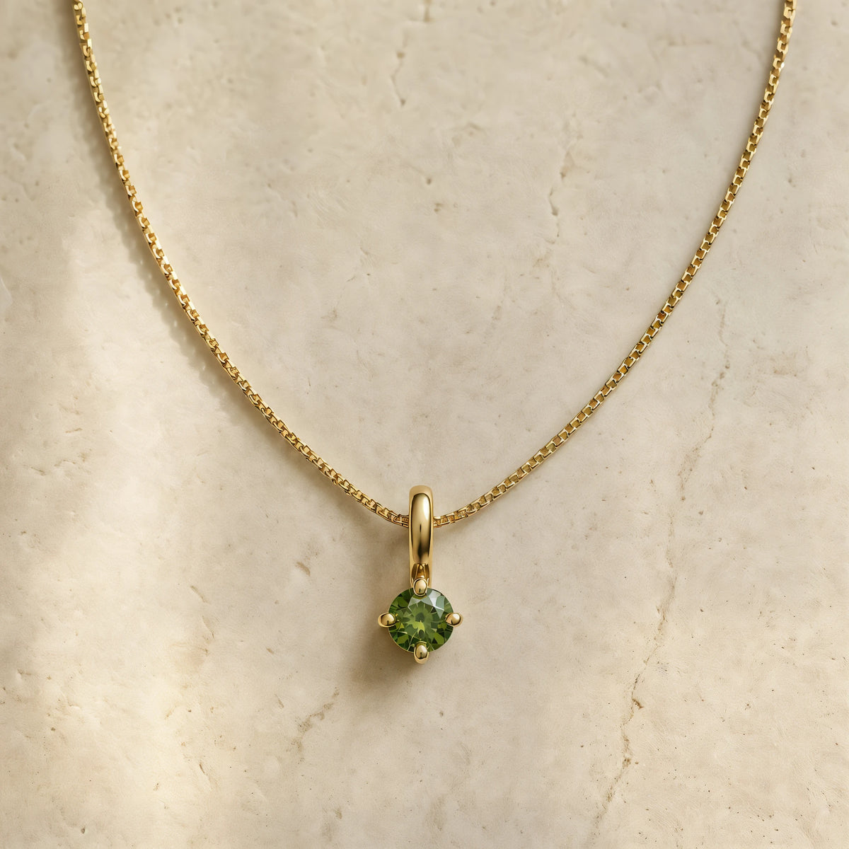 Collier Saral diamant vert en or jaune 18 carats, chaîne fine posée sur travertin