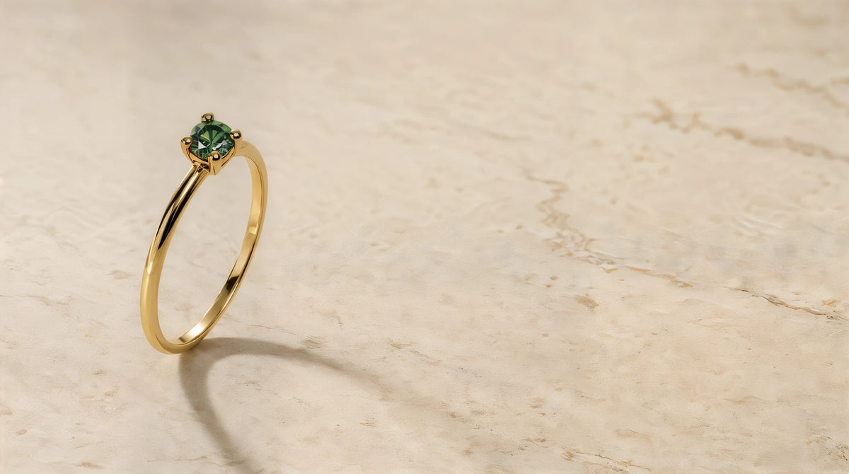 Bague Saral diamant vert en or jaune 18 carats posée sur pierre de travertin, lumière douce